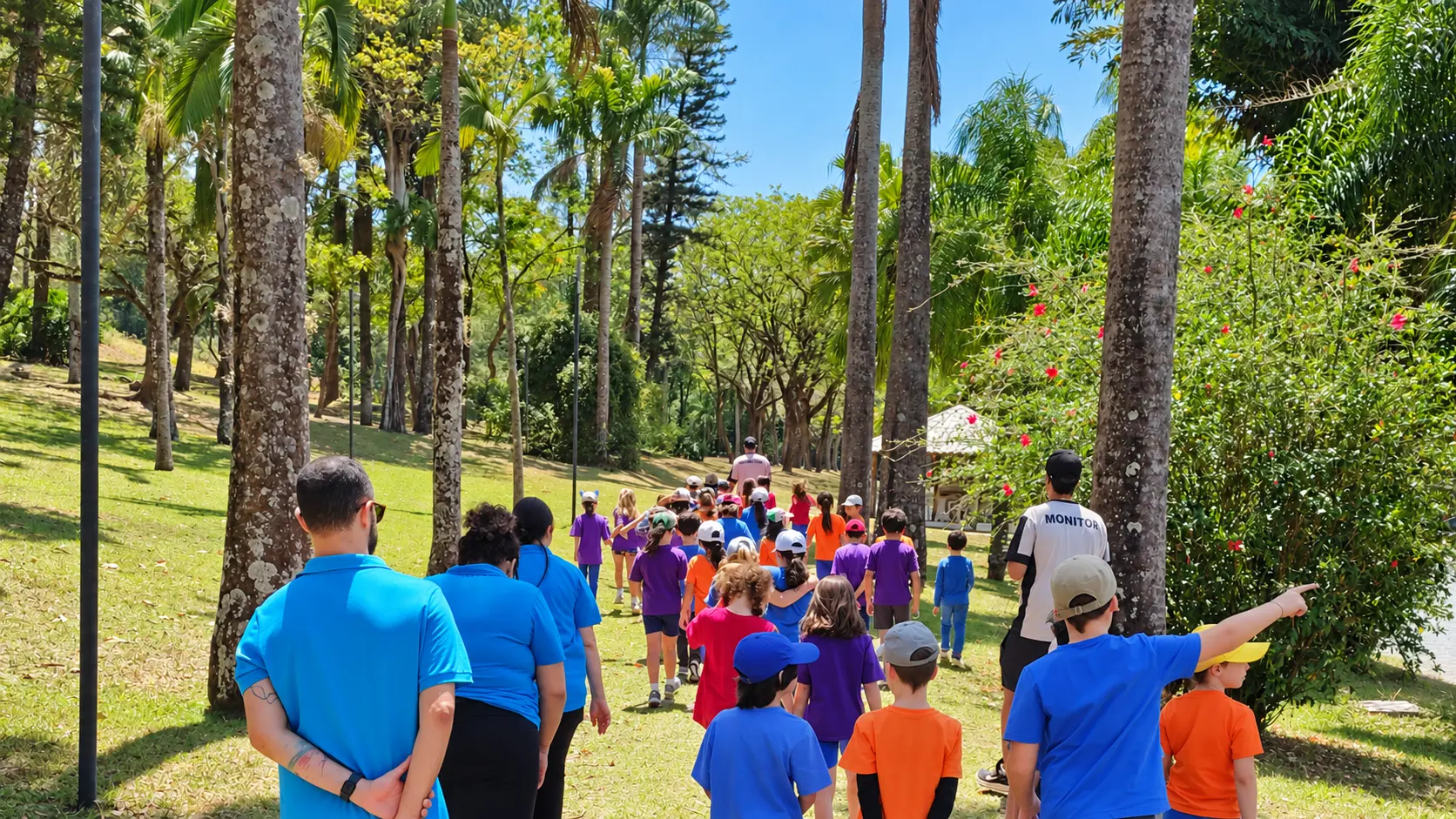 Alunos e professores da Trails School caminhando juntos por um parque arborizado, em saída pedagógica