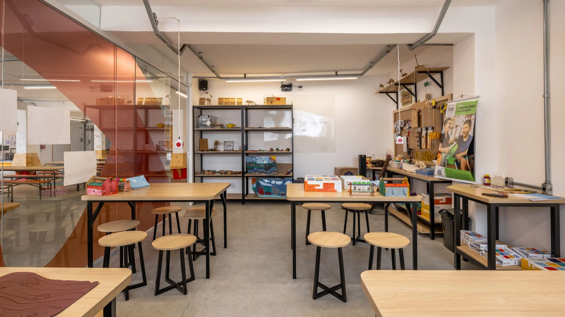 STEM Lab da Trails School, com bancadas, banquetas, estantes de materiais e painel de ferramentas
